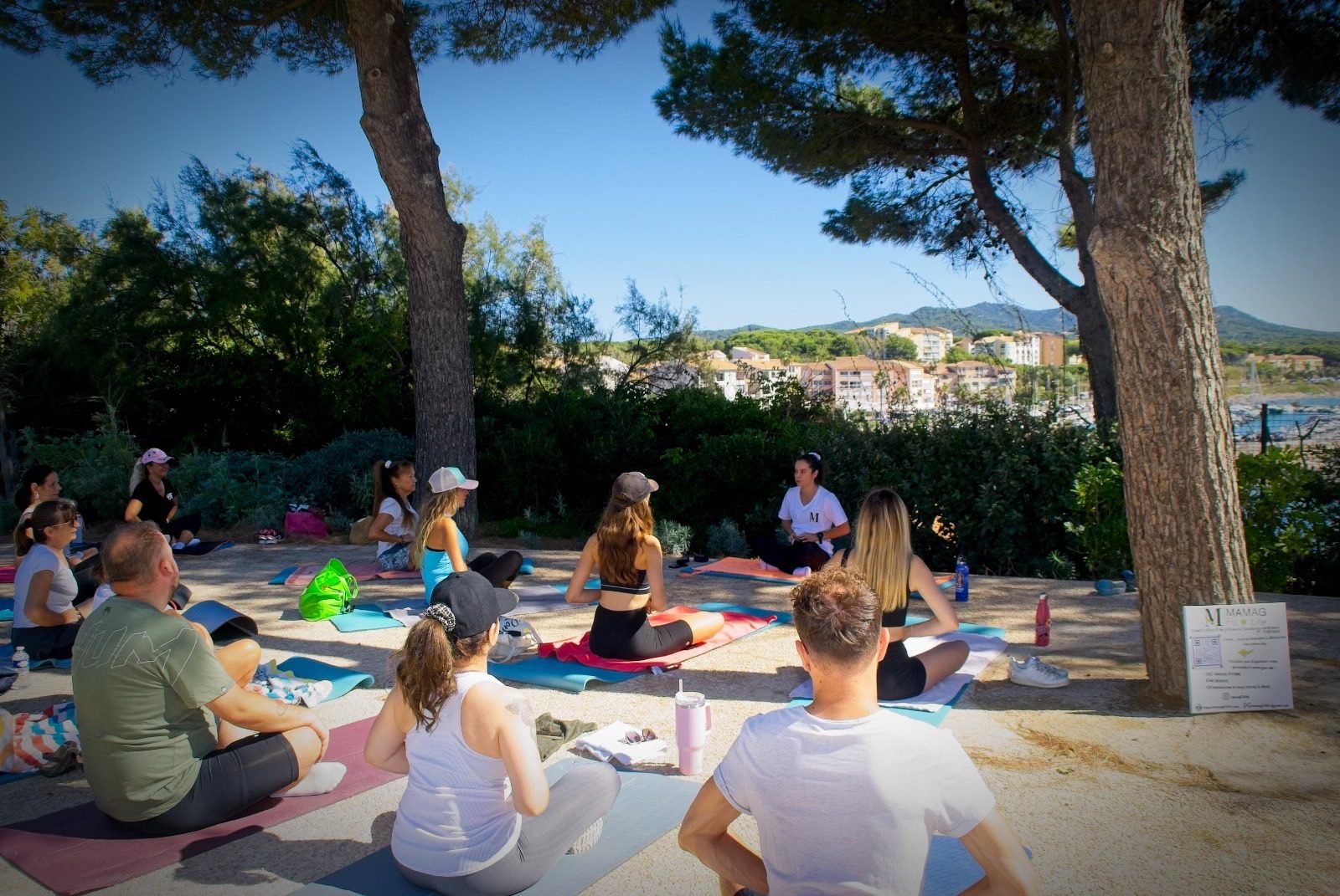 Cours de Pilates en groupe en extérieur, avec instructrice et participants sur tapis.